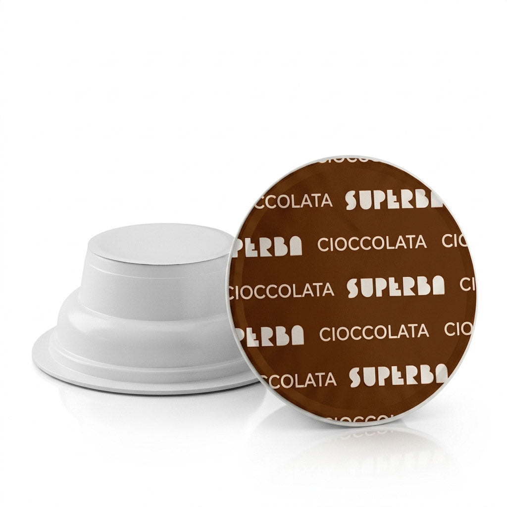 Dettaglio di due capsule Covim Superba Cioccolata: una mostrata di profilo con corpo bianco e l'altra vista dall'alto con pellicola marrone e scritte bianche.